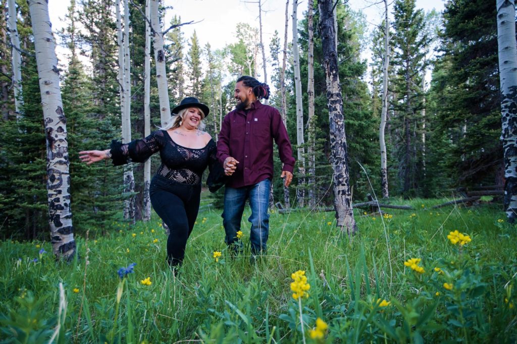 engaged couple frolics through mountain wildflower field