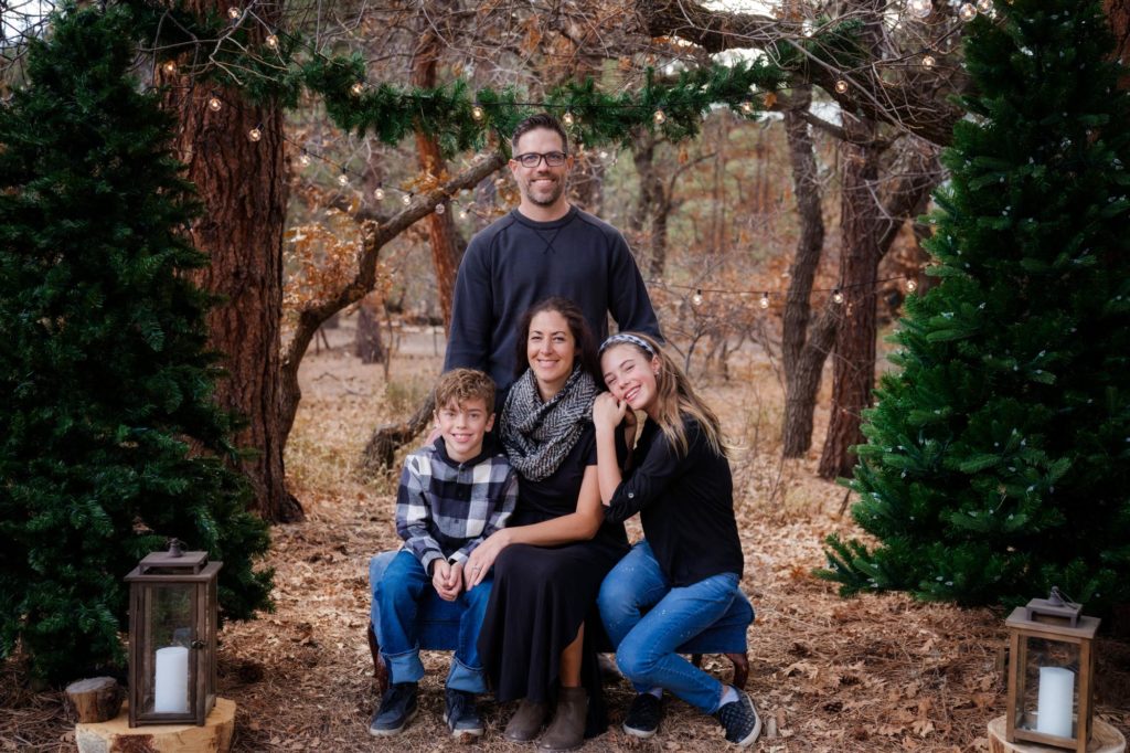 family poses under holiday lights