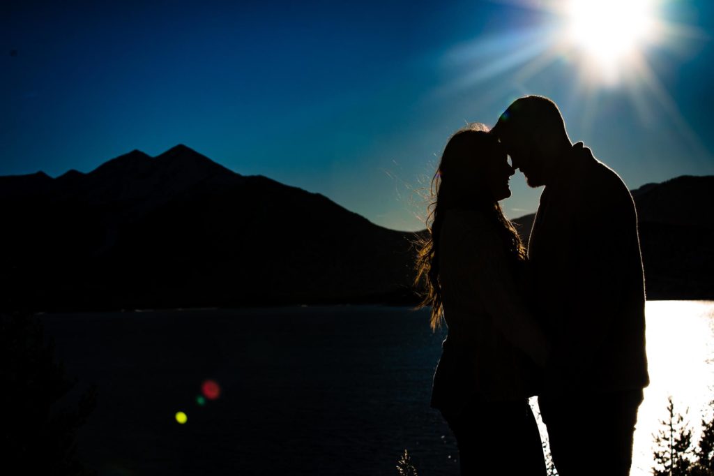 couple poses for winter engagement photos at Lake Dillon
