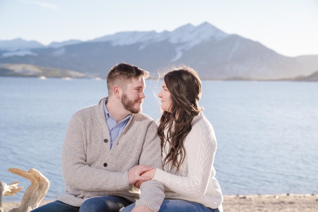 newly engaged couple look at each other in front of Colorado mountains