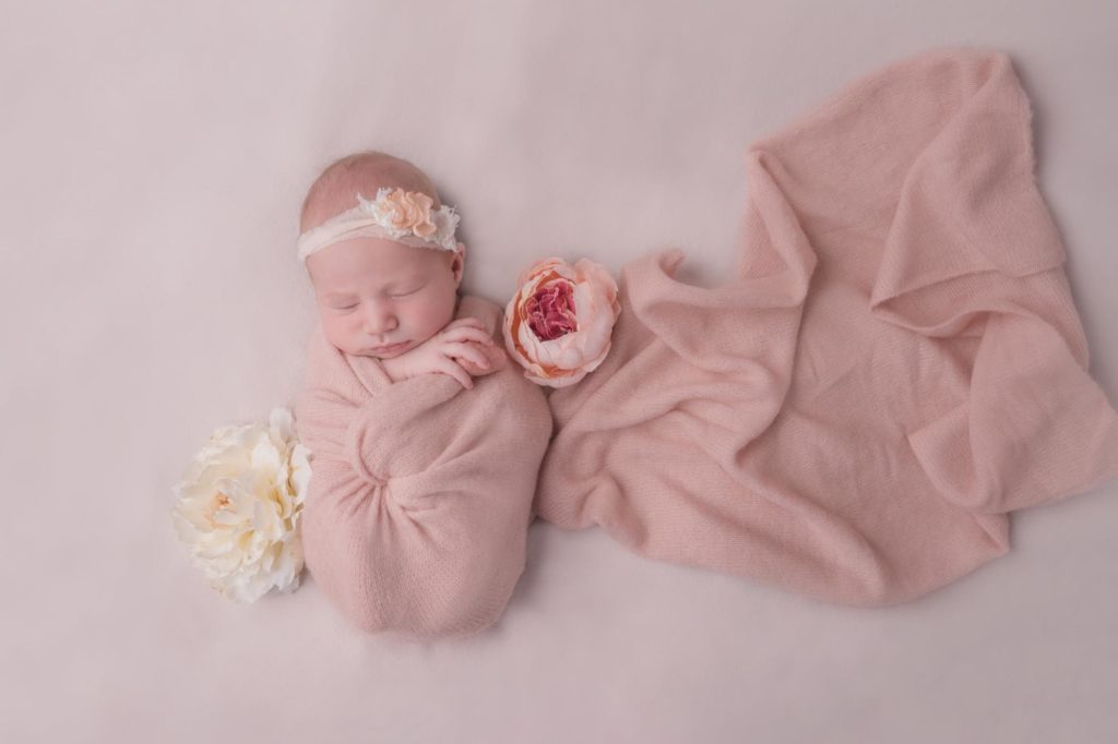 baby in newborn wrap with floral headband