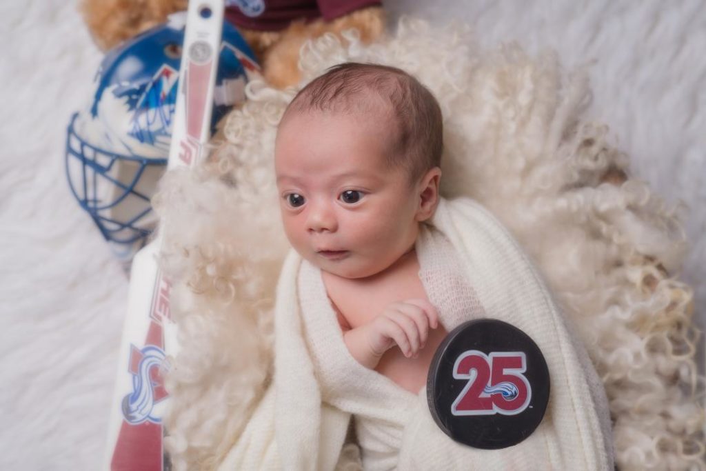 newborn baby posed with hockey puck