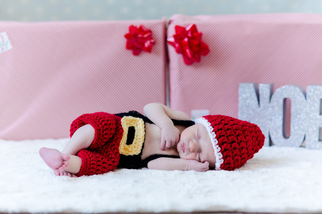 Newborn in Santa outfit in front of 2 presents