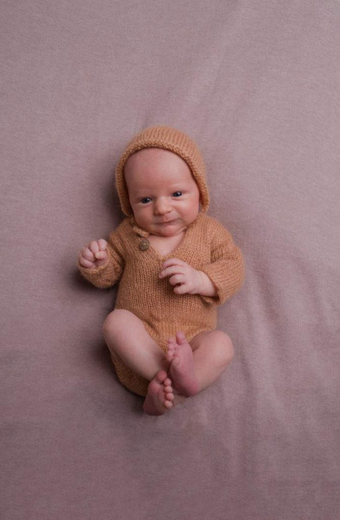 in home newborn photos in a romper and bonnet